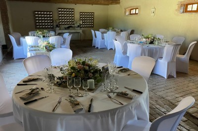 Château en briques rouges entouré de pelouses et d'arbres, sous un ciel clair et ensoleillé.
