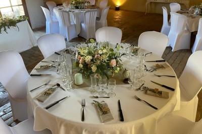 Château en briques rouges entouré de pelouses et d'arbres, sous un ciel clair et ensoleillé.