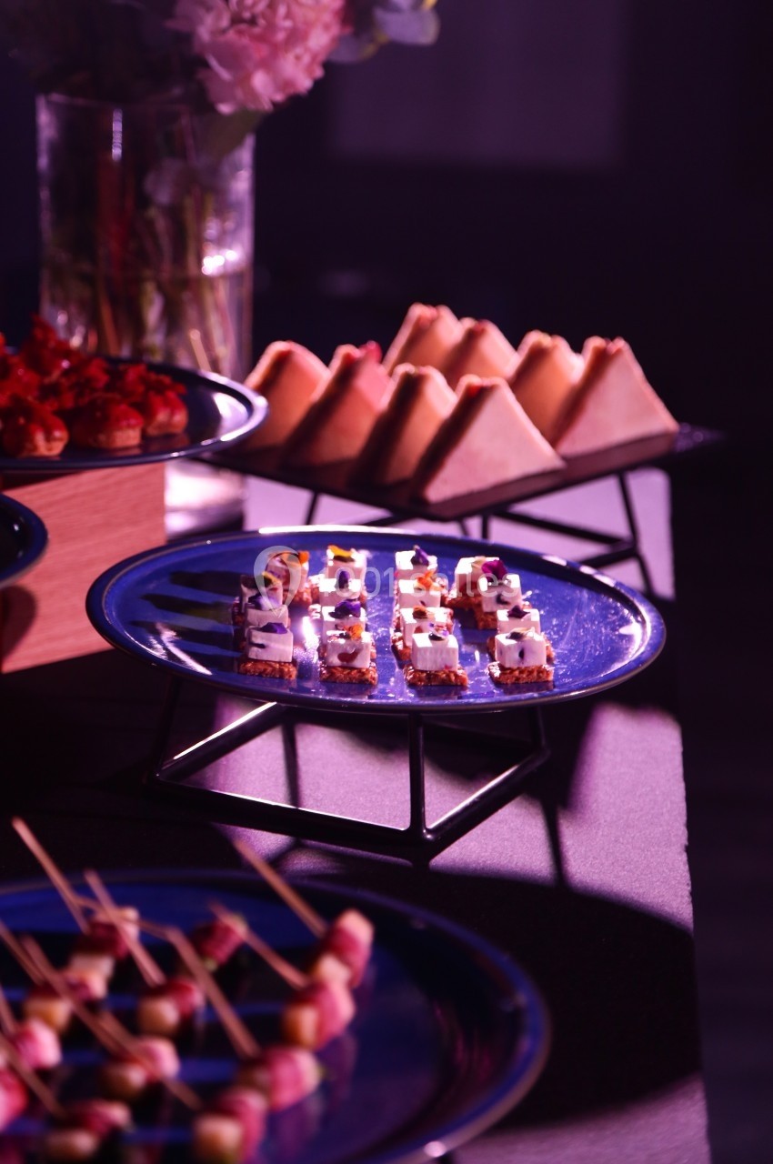 Plateaux de bouchées apéritives variées disposées sur des assiettes dans une ambiance lumineuse tamisée.