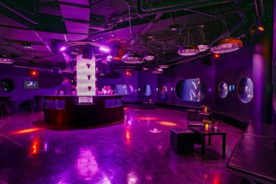 Tunnel d'aquarium avec un grand bassin à droite, éclairages colorés et écran lumineux sur le mur gauche.