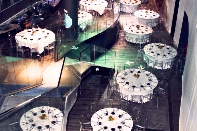 Tunnel d'aquarium avec un grand bassin à droite, éclairages colorés et écran lumineux sur le mur gauche.