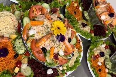 Table de réception élégamment dressée avec chandeliers, fleurs pourpres et vaisselle raffinée dans une salle lumineuse.
