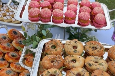 Table de réception élégamment dressée avec chandeliers, fleurs pourpres et vaisselle raffinée dans une salle lumineuse.