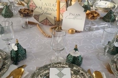 Table de réception élégamment dressée avec chandeliers, fleurs pourpres et vaisselle raffinée dans une salle lumineuse.