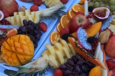 Table de réception élégamment dressée avec chandeliers, fleurs pourpres et vaisselle raffinée dans une salle lumineuse.