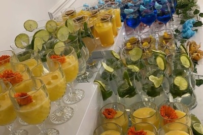 Table de réception élégamment dressée avec chandeliers, fleurs pourpres et vaisselle raffinée dans une salle lumineuse.