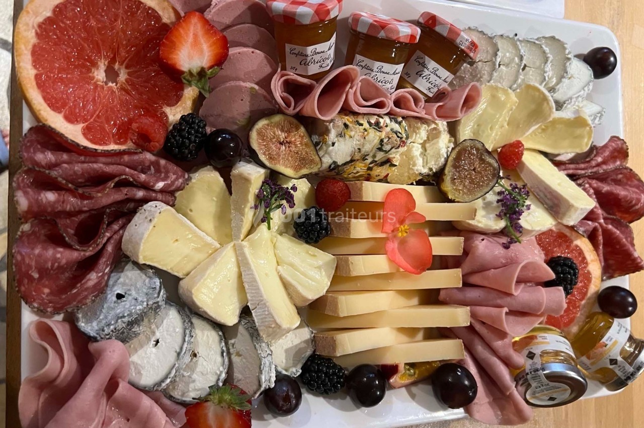 Plateau garni de charcuteries, fromages variés, fruits frais, confitures et décorations florales.