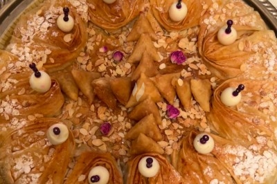 Table de réception élégamment dressée avec chandeliers, fleurs pourpres et vaisselle raffinée dans une salle lumineuse.