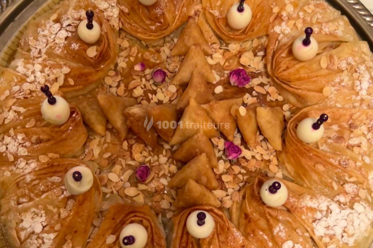 Plateau de pâtisseries orientales variées, décorées d'amandes effilées, de roses séchées et de touches de chocolat blanc.