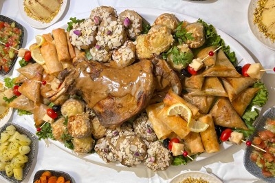 Table de réception élégamment dressée avec chandeliers, fleurs pourpres et vaisselle raffinée dans une salle lumineuse.
