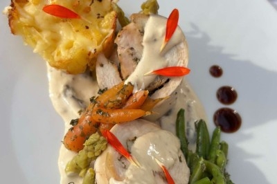 Table de réception élégamment dressée avec chandeliers, fleurs pourpres et vaisselle raffinée dans une salle lumineuse.