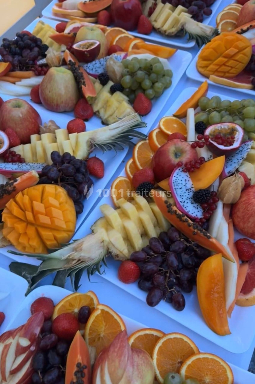 Assortiment de fruits frais variés, incluant mangues, raisins, pommes, oranges, fraises et fruits exotiques, disposés sur…