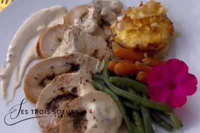 Table de réception élégamment dressée avec chandeliers, fleurs pourpres et vaisselle raffinée dans une salle lumineuse.