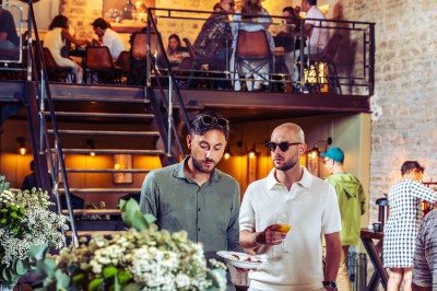 Façade en pierre éclairée d'une bâtisse ancienne avec une enseigne lumineuse, vue de nuit.