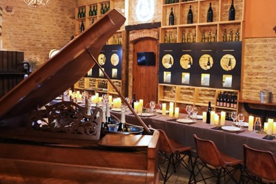 Façade en pierre éclairée d'une bâtisse ancienne avec une enseigne lumineuse, vue de nuit.