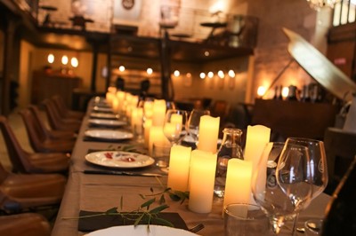 Façade en pierre éclairée d'une bâtisse ancienne avec une enseigne lumineuse, vue de nuit.