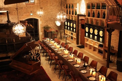 Façade en pierre éclairée d'une bâtisse ancienne avec une enseigne lumineuse, vue de nuit.