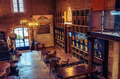 Façade en pierre éclairée d'une bâtisse ancienne avec une enseigne lumineuse, vue de nuit.