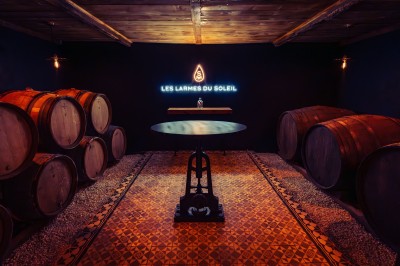 Façade en pierre éclairée d'une bâtisse ancienne avec une enseigne lumineuse, vue de nuit.