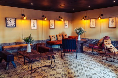 Façade en pierre éclairée d'une bâtisse ancienne avec une enseigne lumineuse, vue de nuit.