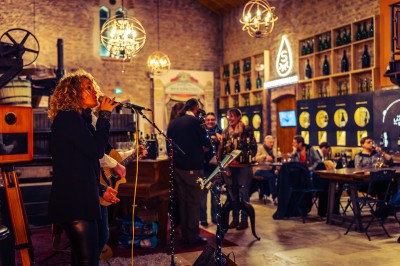 Façade en pierre éclairée d'une bâtisse ancienne avec une enseigne lumineuse, vue de nuit.