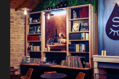 Façade en pierre éclairée d'une bâtisse ancienne avec une enseigne lumineuse, vue de nuit.