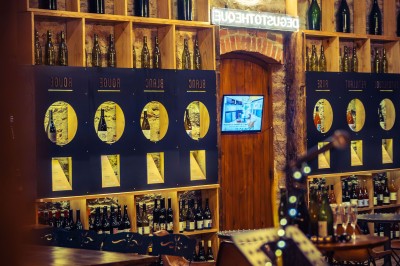 Façade en pierre éclairée d'une bâtisse ancienne avec une enseigne lumineuse, vue de nuit.