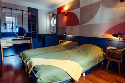 Façade en pierre éclairée d'une bâtisse ancienne avec une enseigne lumineuse, vue de nuit.