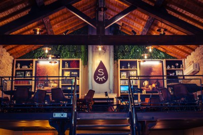 Façade en pierre éclairée d'une bâtisse ancienne avec une enseigne lumineuse, vue de nuit.