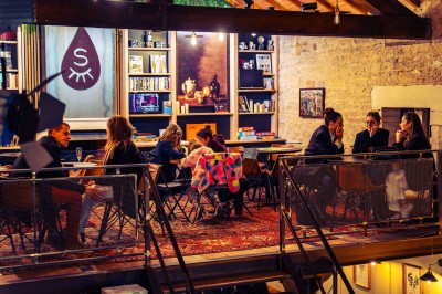 Façade en pierre éclairée d'une bâtisse ancienne avec une enseigne lumineuse, vue de nuit.