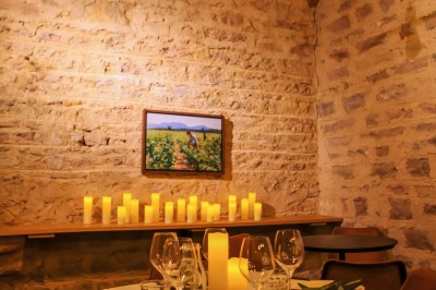 Façade en pierre éclairée d'une bâtisse ancienne avec une enseigne lumineuse, vue de nuit.
