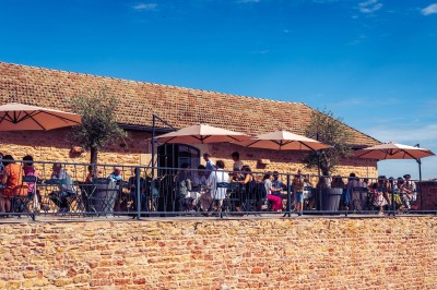 Façade en pierre éclairée d'une bâtisse ancienne avec une enseigne lumineuse, vue de nuit.