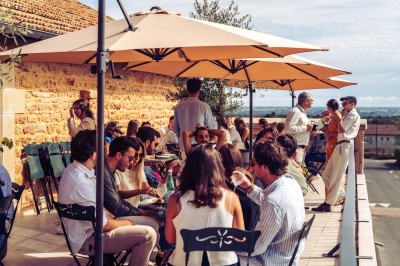Façade en pierre éclairée d'une bâtisse ancienne avec une enseigne lumineuse, vue de nuit.