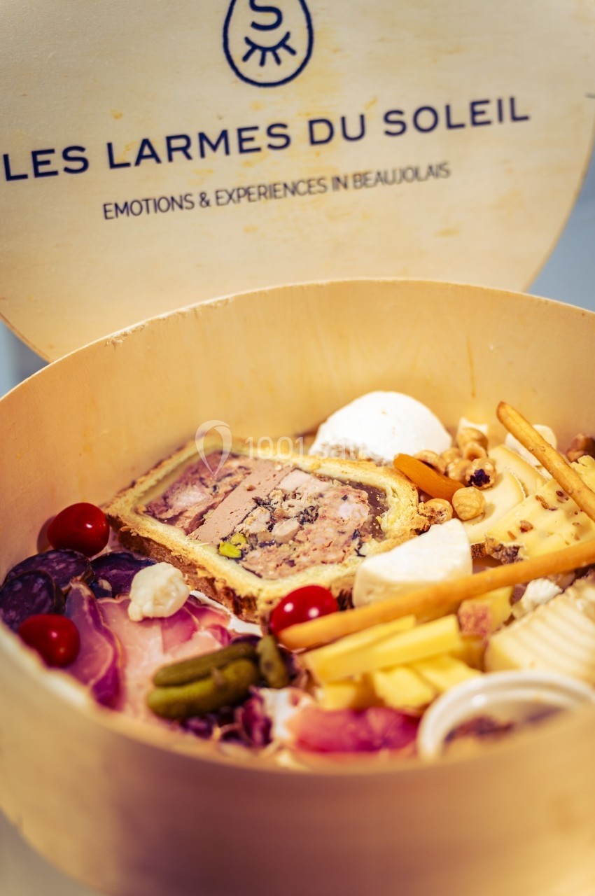 Plateau en bois contenant des charcuteries, fromages, pâté en croûte et accompagnements variés.