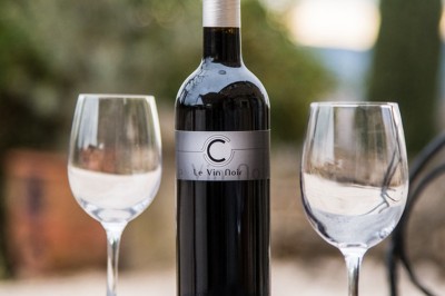 Façade d'un bâtiment en pierre éclairée la nuit, entourée de végétation sombre.