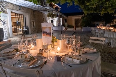 Façade d'un bâtiment en pierre éclairée la nuit, entourée de végétation sombre.