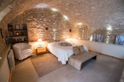 Façade d'un bâtiment en pierre éclairée la nuit, entourée de végétation sombre.