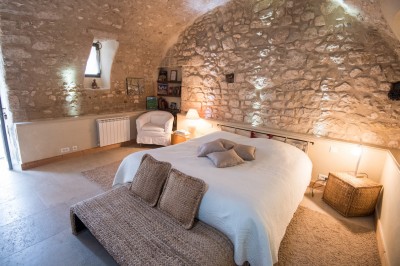 Façade d'un bâtiment en pierre éclairée la nuit, entourée de végétation sombre.