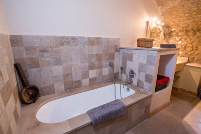 Façade d'un bâtiment en pierre éclairée la nuit, entourée de végétation sombre.