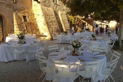 Façade d'un bâtiment en pierre éclairée la nuit, entourée de végétation sombre.