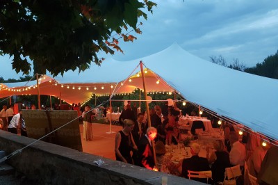Façade d'un bâtiment en pierre éclairée la nuit, entourée de végétation sombre.