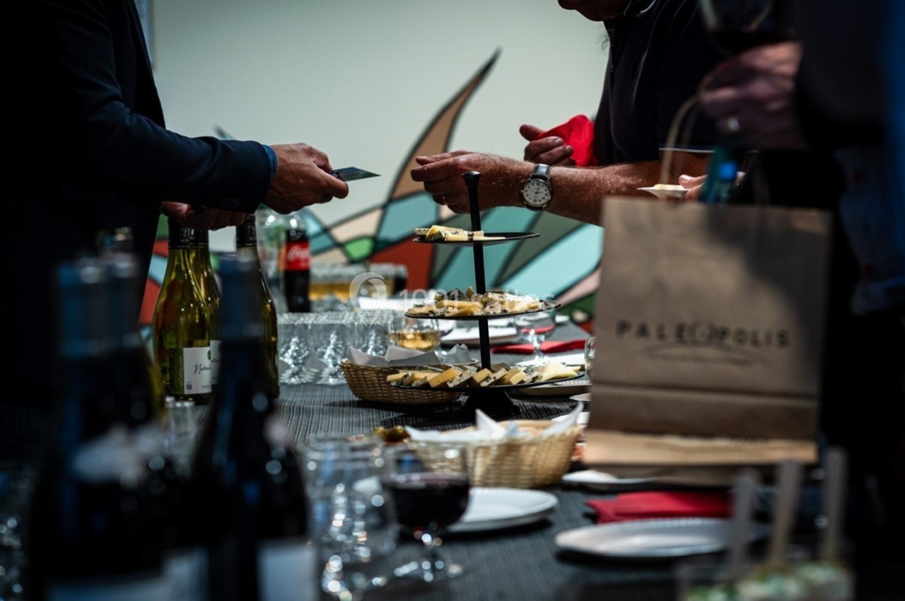Personnes se servant de nourriture et de boissons sur une table garnie lors d'un événement ou d'une réception.
