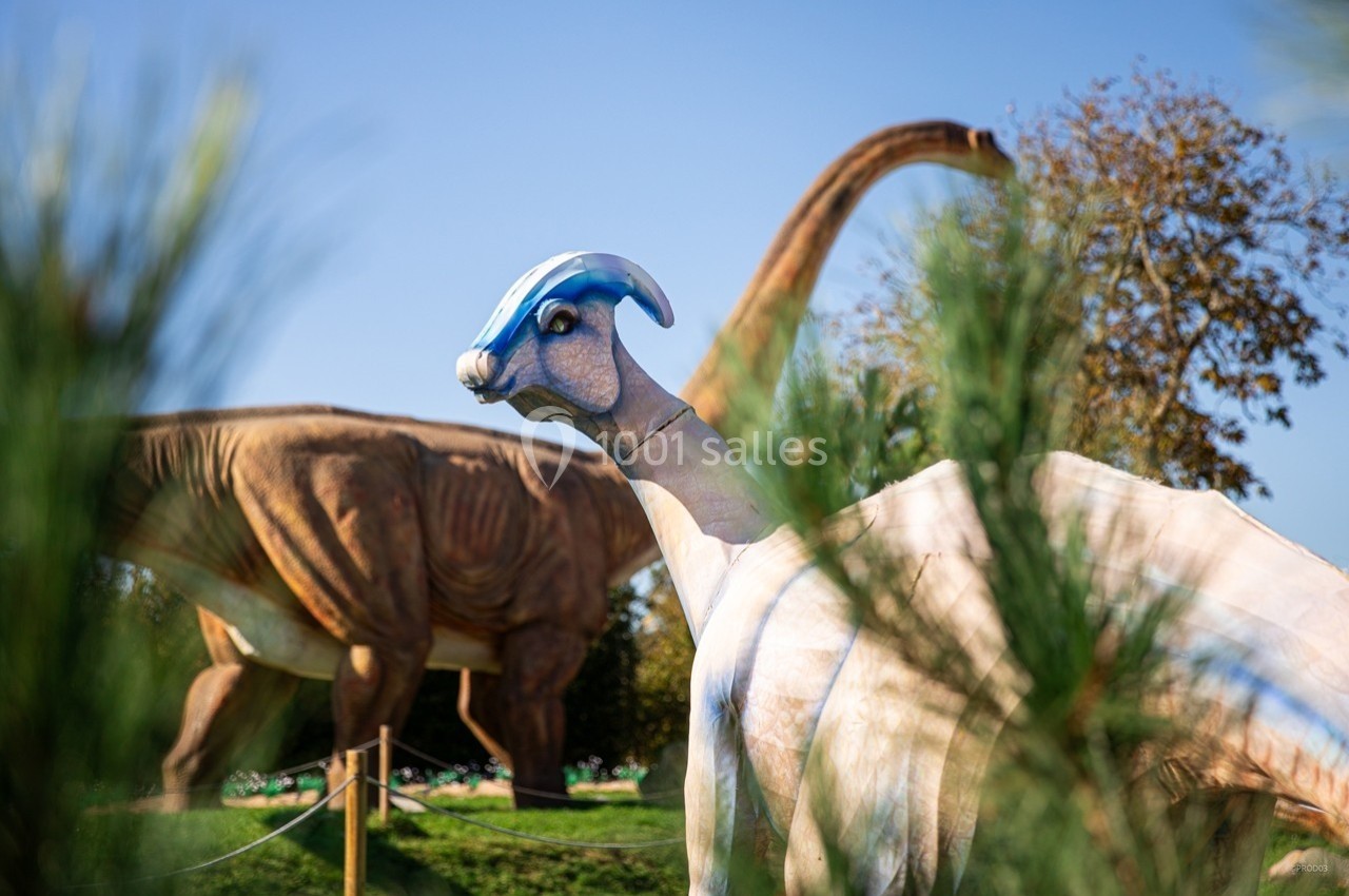 Reproduction de dinosaures dans un parc, avec un parasaurolophus au premier plan et un brachiosaure en arrière-plan.