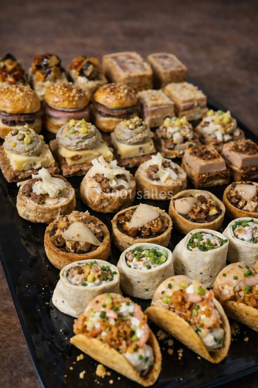 Plateau de bouchées apéritives variées comprenant tartelettes, wraps, mini-sandwichs et autres amuse-bouches.