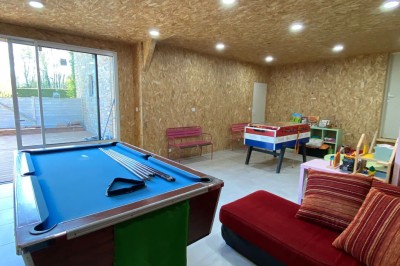 Cuisine professionnelle avec équipements en acier inoxydable, comprenant un four, des étagères et des plans de travail.