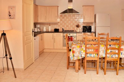 Cuisine professionnelle avec équipements en acier inoxydable, comprenant un four, des étagères et des plans de travail.