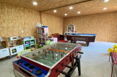 Jardin verdoyant avec pelouse, arbres dénudés, fleurs printanières et ciel bleu parsemé de nuages légers.