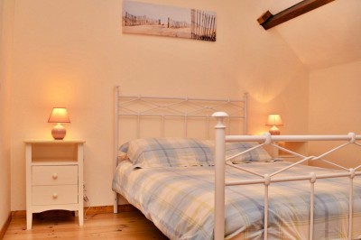 Jardin verdoyant avec pelouse, arbres dénudés, fleurs printanières et ciel bleu parsemé de nuages légers.