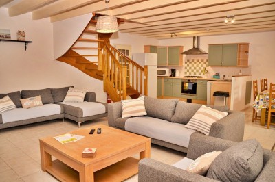 Jardin verdoyant avec pelouse, arbres dénudés, fleurs printanières et ciel bleu parsemé de nuages légers.