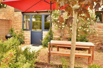 Jardin verdoyant avec pelouse, arbres dénudés, fleurs printanières et ciel bleu parsemé de nuages légers.